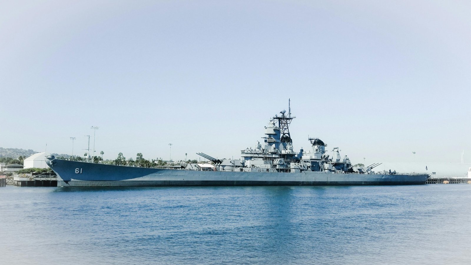 The USS Iowa battleship docked in Los Angeles harbor, California against a clear blue sky.