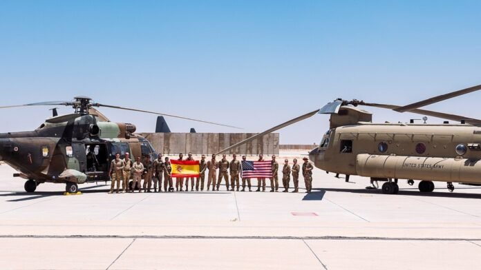 US and Spanish Army soldiers standing in front of helicopters at Al Asad Airbase in Iraq