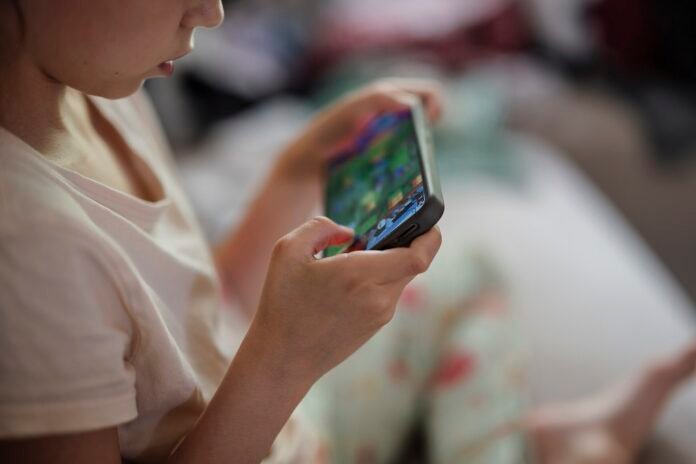 Close-up of a child holding a smartphone and playing a mobile game