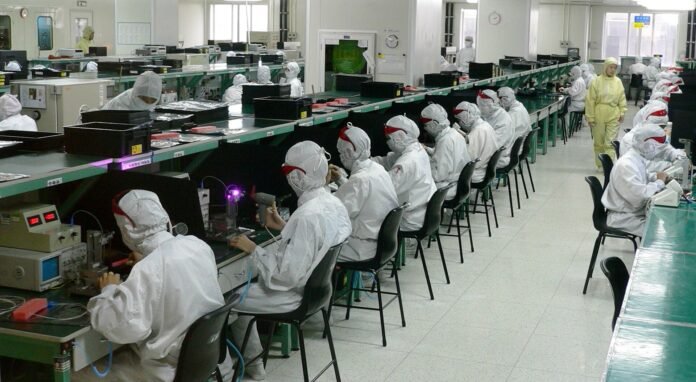 Workers in protective clothing at assembly lines in an electronics factory in Shenzhen, China