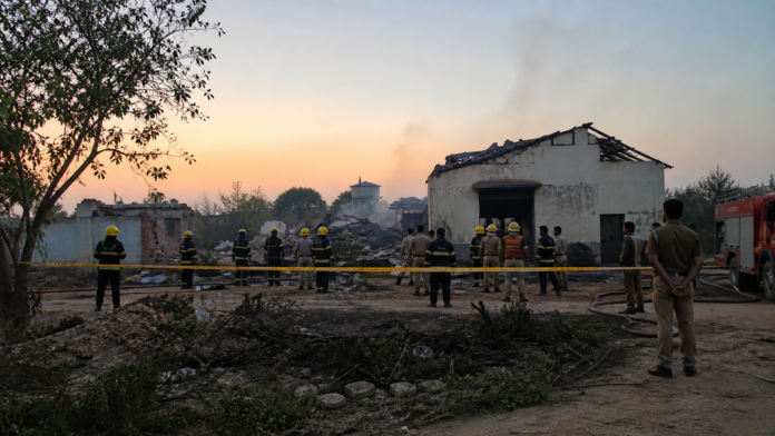 कौशांबी पटाखा फैक्टरी विस्फोट के बाद क्षतिग्रस्त परिसर के बाहर राहत और बचाव कर्मी