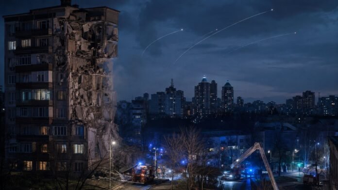 रात में Kyiv शहर के ऊपर missile alert और क्षतिग्रस्त आवासीय इमारत का संपादकीय चित्र