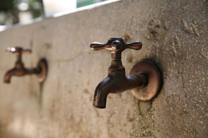 Detailed shot of vintage metal water taps on a textured concrete wall, capturing rustic charm.