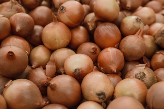 Fresh organic brown onions piled together showcasing natural texture in a close-up shot.