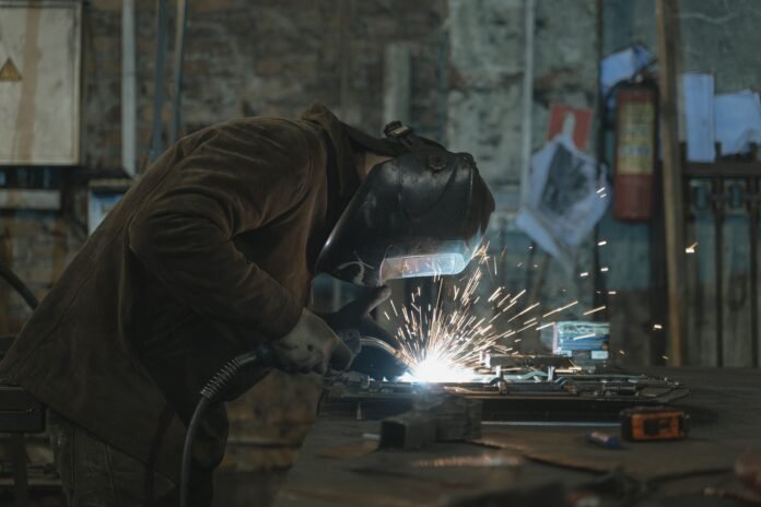 Representative photograph of a welder wearing protective equipment at work in a workshop